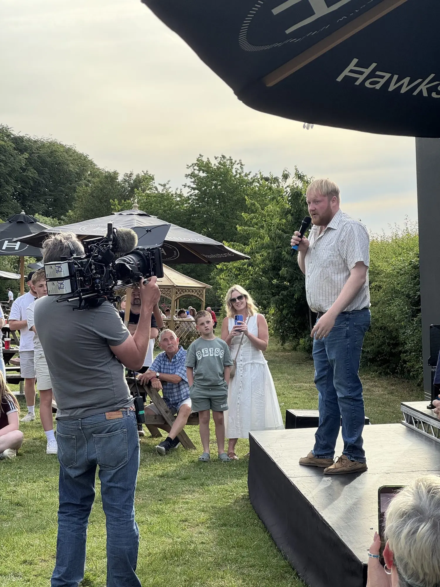 Camera operator filming a speaker on stage beside the LED wall