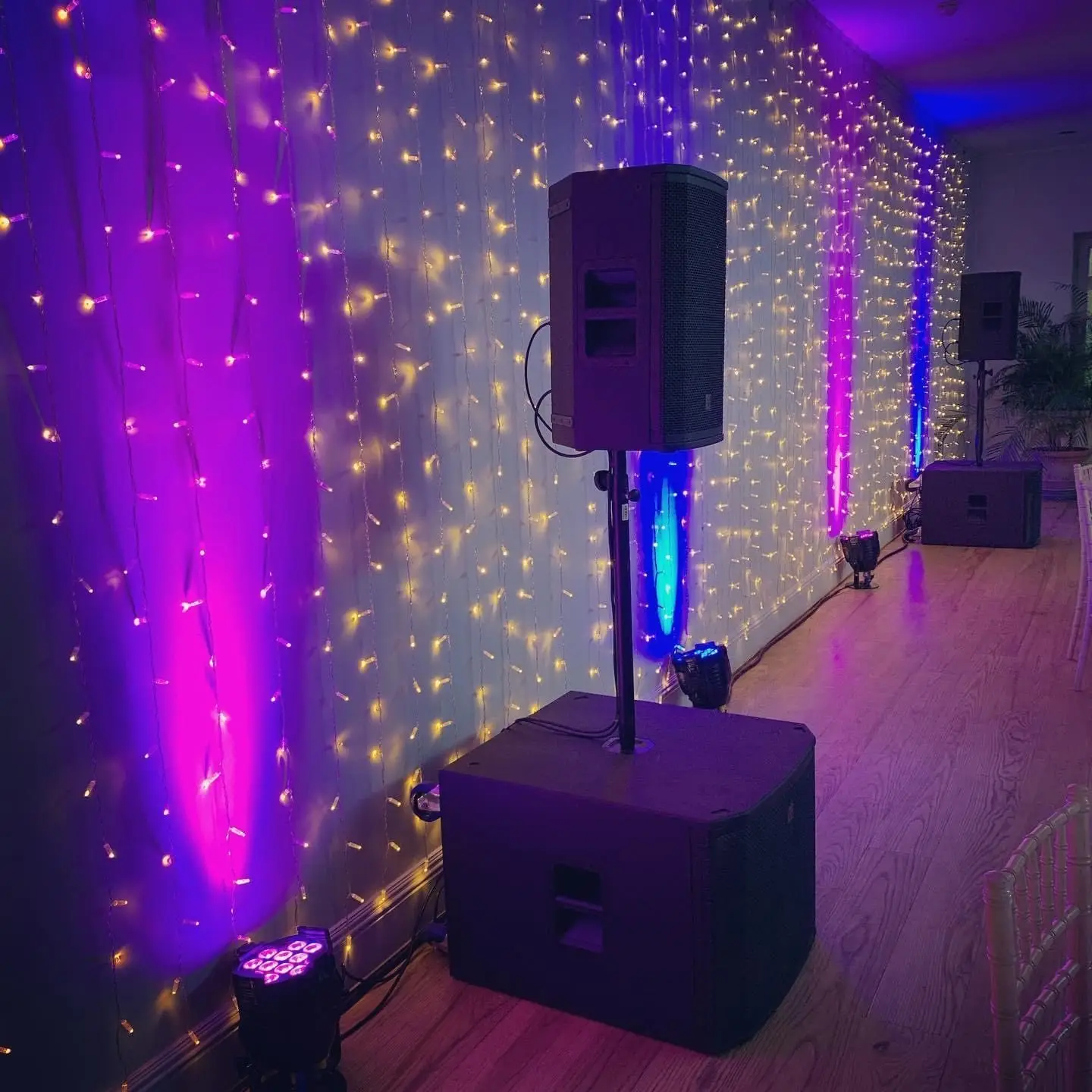 Purple LED uplighting behind a fairy-light curtain beside a loudspeaker at a venue
