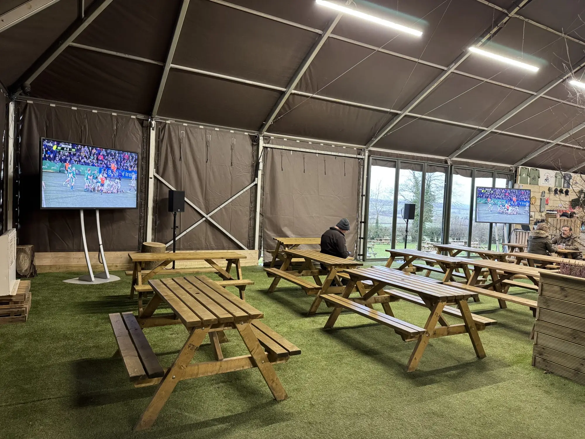 Large display screens set up in a marquee with picnic benches