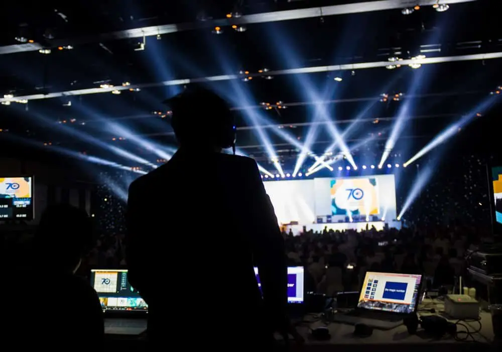 Conference hall with white beams of light over the audience and stage