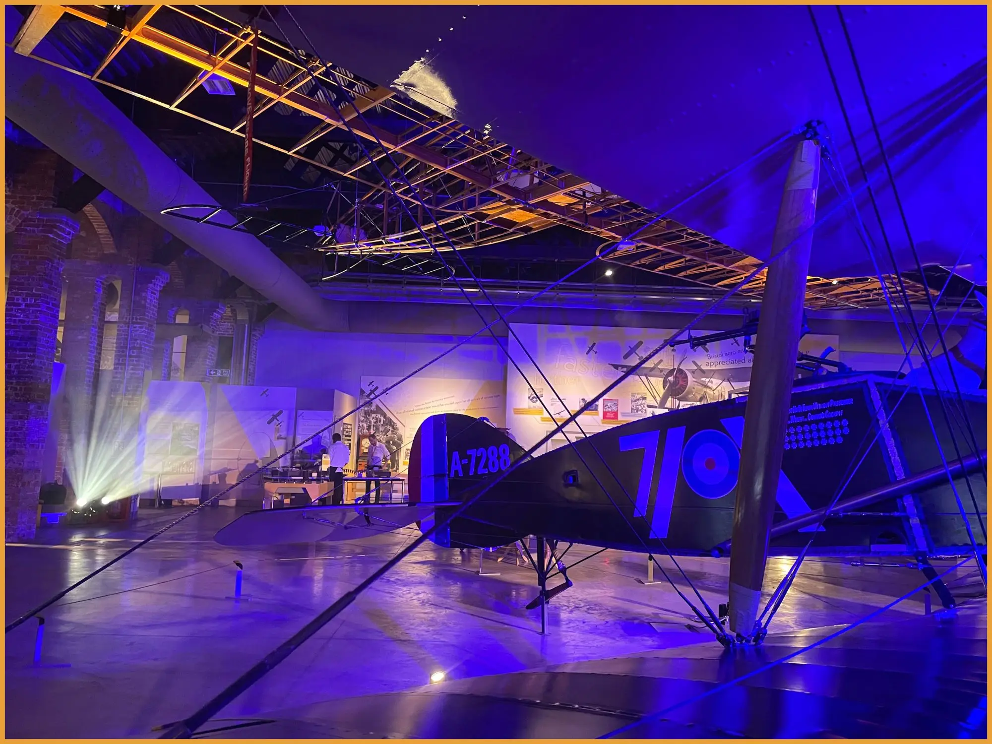 Historic biplane in the Aerospace Bristol hangar washed in deep blue light