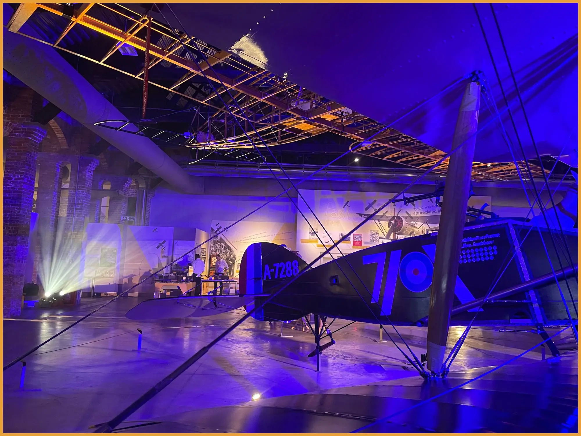 Historic biplane in the Aerospace Bristol hangar washed in deep blue light