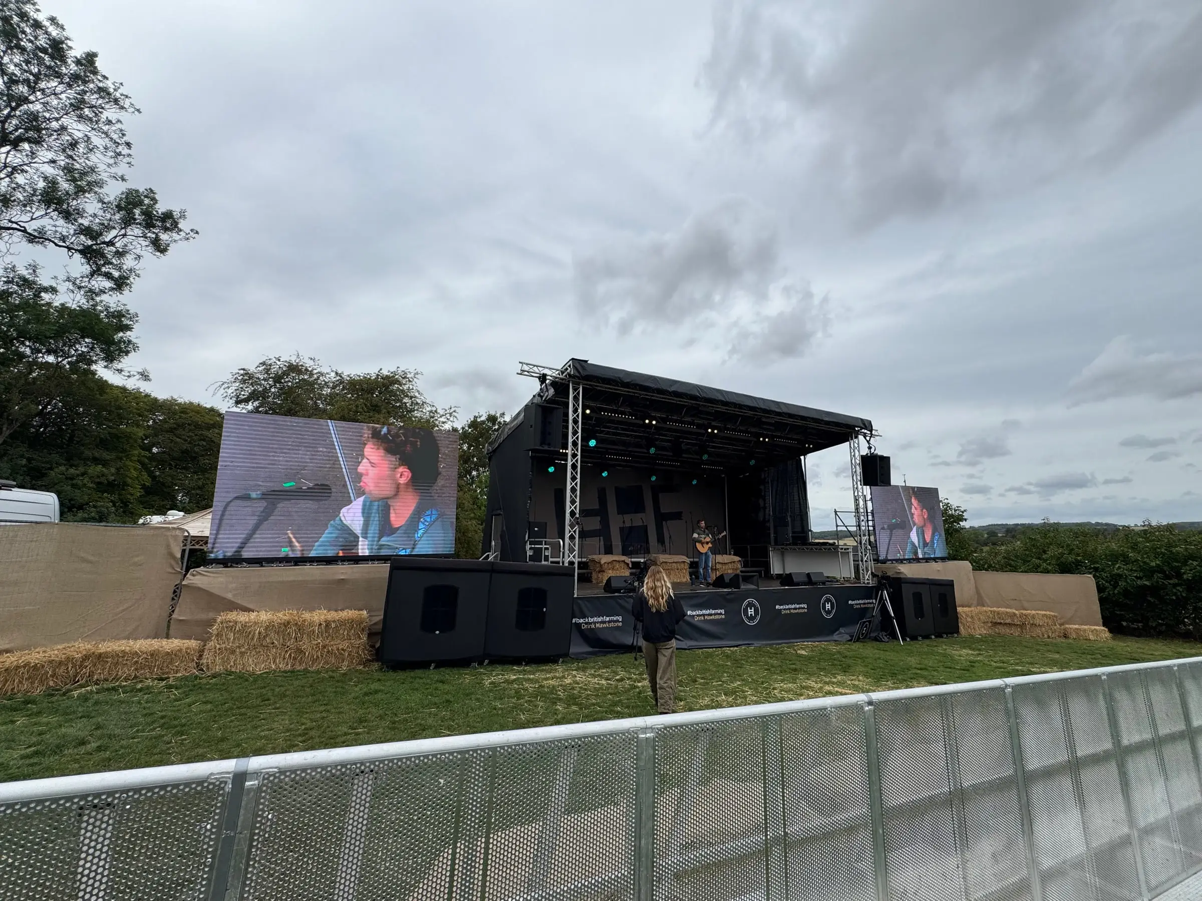 Outdoor stage flanked by two LED screens, with Danley loudspeakers along the front