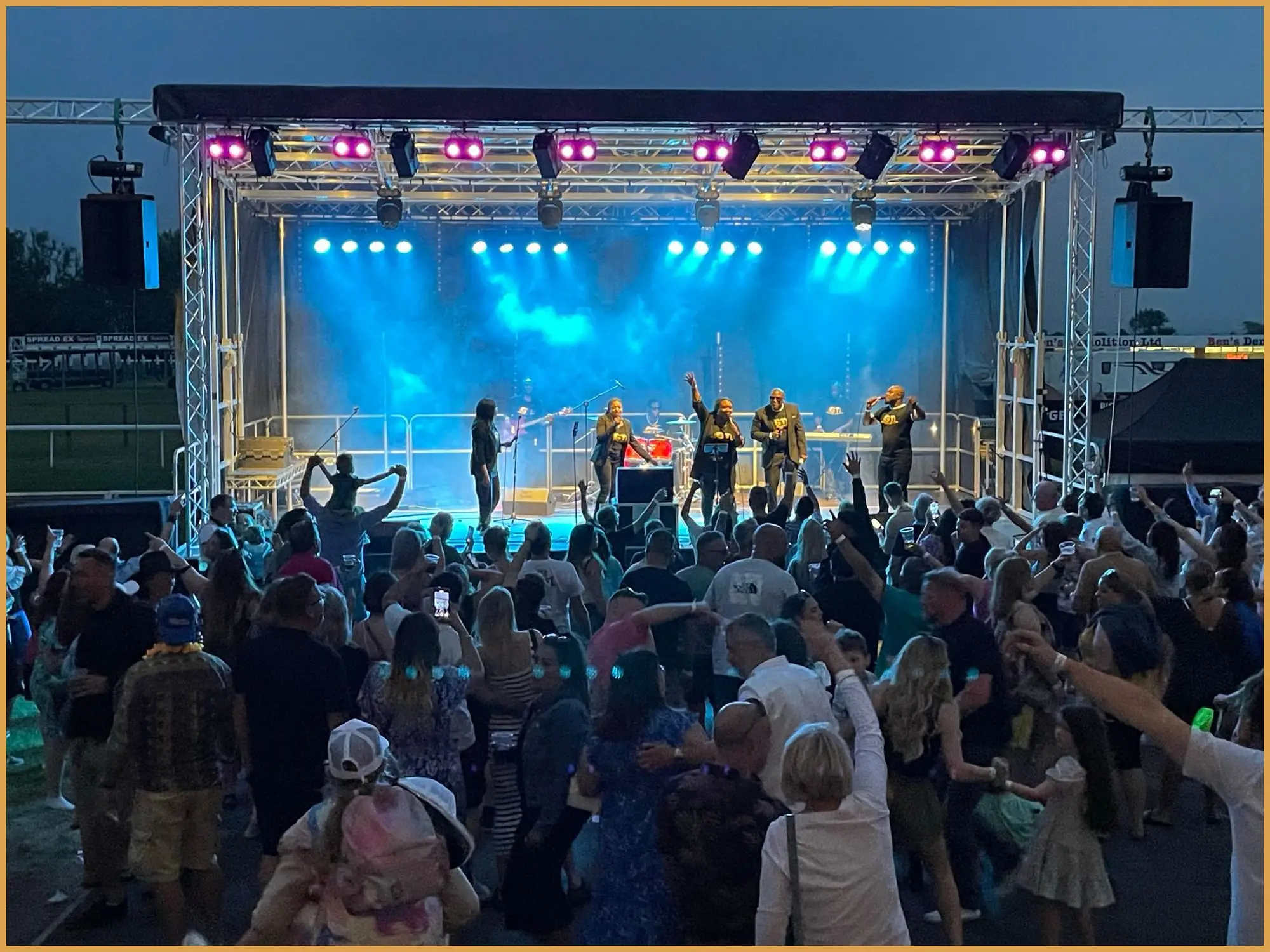 Festival stage lit in blue with performers and a crowd