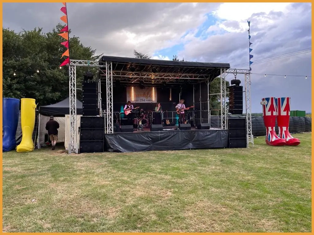 Festival stage in a field with a band performing in daylight