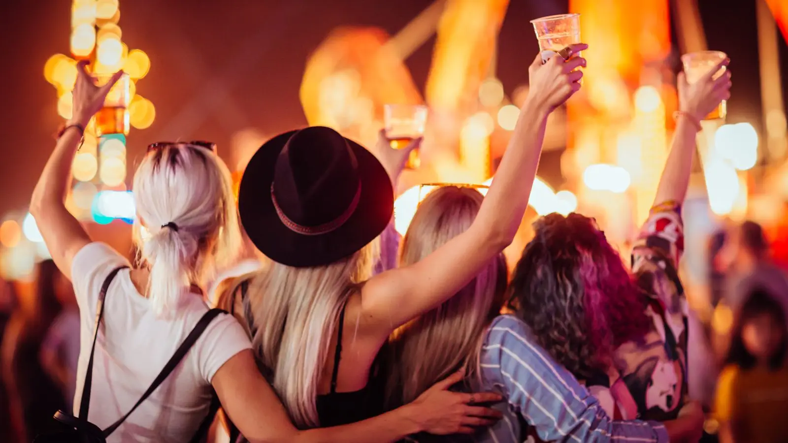 Festival crowd with hands in the air in front of a lit stage