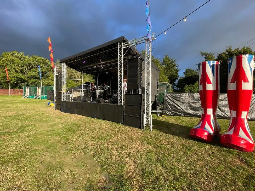Stage in a field with giant Union Jack wellies beside it
