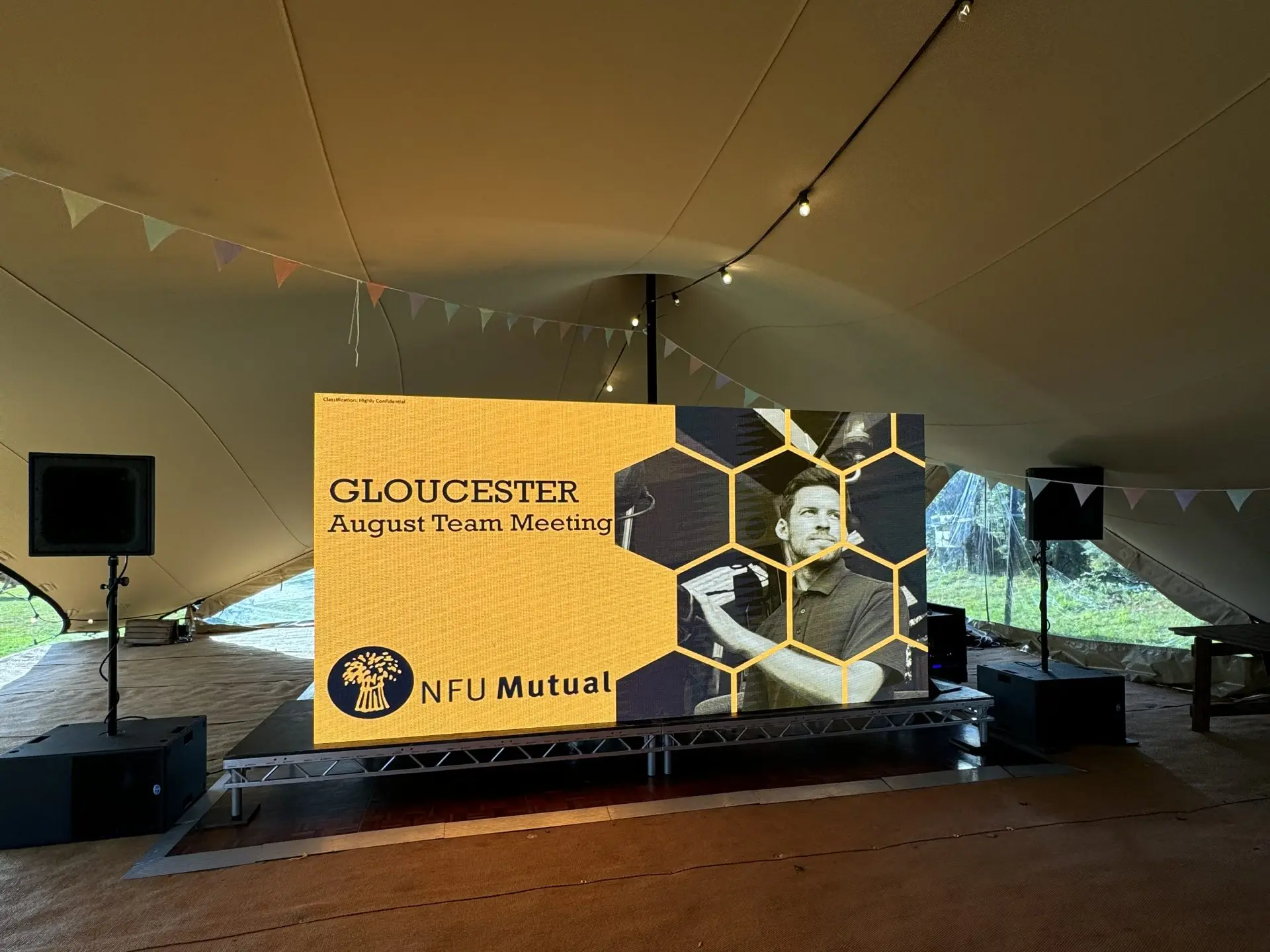 4m x 2m LED video wall on a stage deck inside a stretch tent, showing the NFU Mutual team meeting title slide